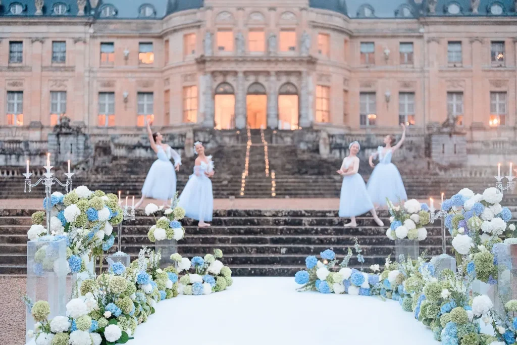 Candlelit luxury proposal at Chateau de Vaux-le-Vicomte with blue-white florals and four ballerinas, planned by Kiss Me in Paris.