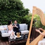 Christina and Vahe share their first toast as a newly engaged couple on the Peninsula's Secret Table terrace while a master harpist and violinist perform a private concerto. This intimate post-proposal setting showcases the complete Eiffel Tower luxury experience available when you work with Kiss Me in Paris.