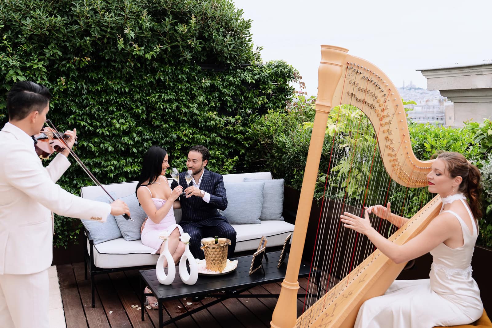 Christina and Vahe share their first toast as a newly engaged couple on the Peninsula's Secret Table terrace while a master harpist and violinist perform a private concerto. This intimate post-proposal setting showcases the complete Eiffel Tower luxury experience available when you work with Kiss Me in Paris.