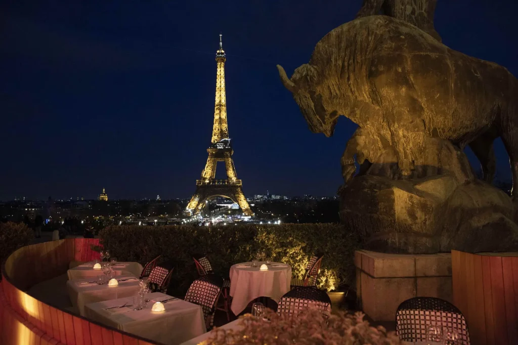 Café de l'Homme restaurant terrace at night with illuminated Eiffel Tower view, Paris