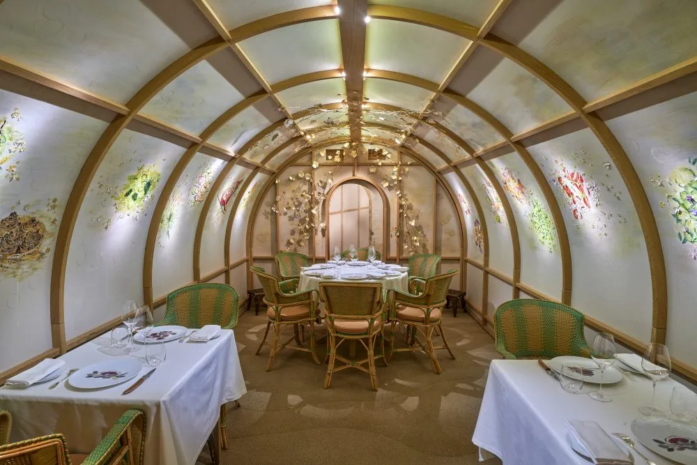 Arpège Paris restaurant intimate barrel-vaulted private dining room with botanical murals, rattan chairs and arched wooden ribs