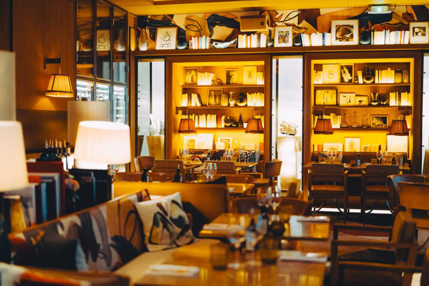 Brach Paris restaurant cosy dining room with illuminated bookshelves, table lamps and artistic decor