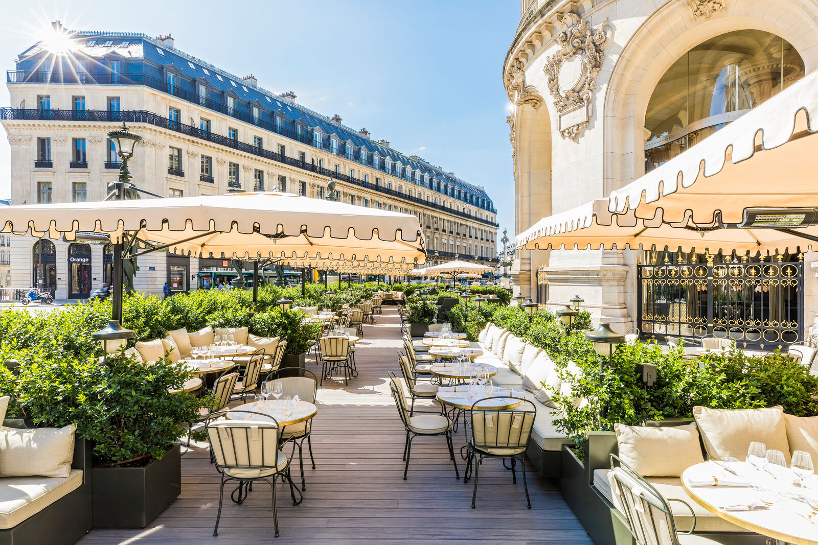 Coco Paris restaurant sunny outdoor terrace at the Palais Garnier Opera with cream parasols and boxwood hedging