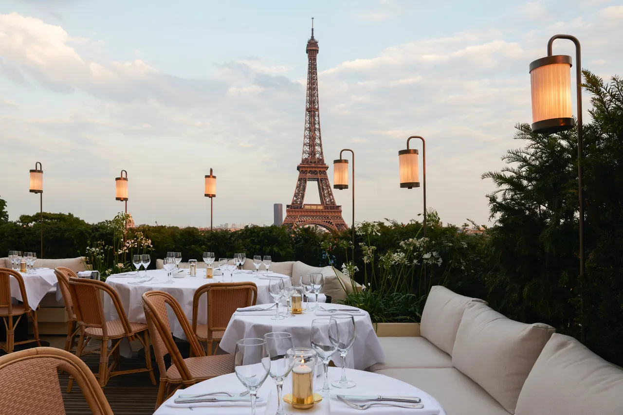 Girafe Paris restaurant rooftop terrace at dusk with Eiffel Tower perfectly framed by lanterns and greenery