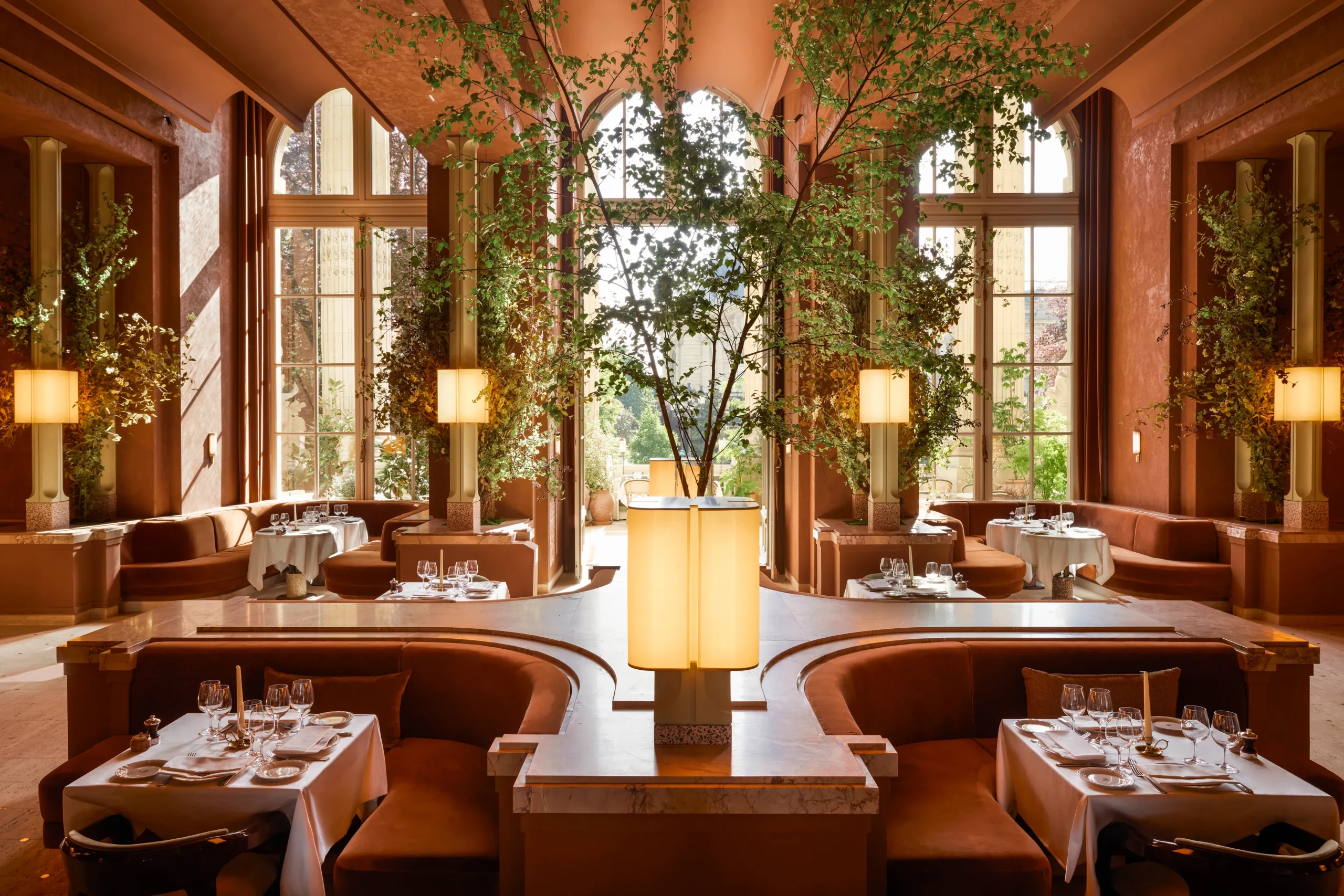 Le Grand Café Paris restaurant warm terracotta dining room with indoor trees and arched windows