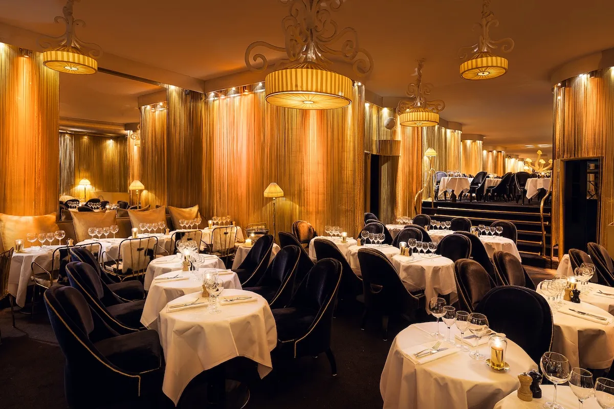 Le Matignon Paris restaurant golden Art Deco dining room with navy velvet chairs, striped pendant lights and mirrored walls