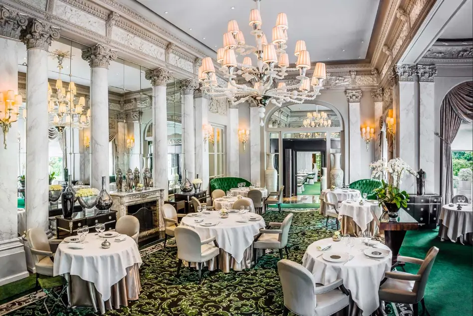 Le Pré Catelan Paris restaurant grand dining room with marble columns, white Murano chandelier and emerald green carpet in the Bois de Boulogne