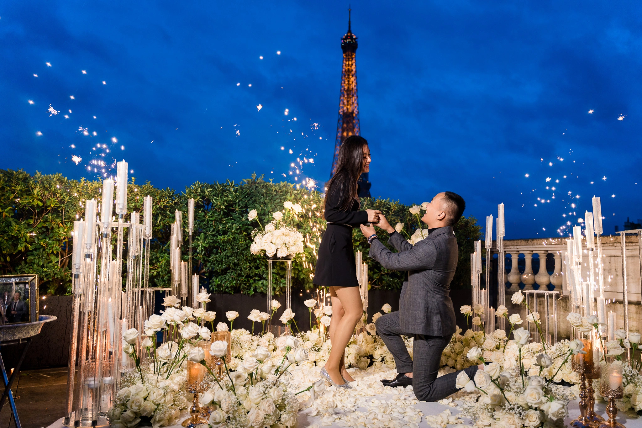 Full-production private proposal on the Shangri-La Paris terrace. White rose floor installation, crystal candelabras, hand sparklers, Eiffel Tower view. Planned and produced by Kiss Me in Paris.