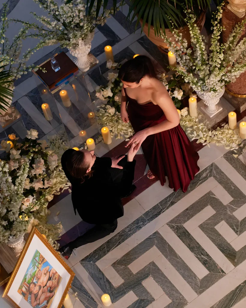Aerial view of couple during proposal on marble floor lined with candles and white florals, Musée Jacquemart-André