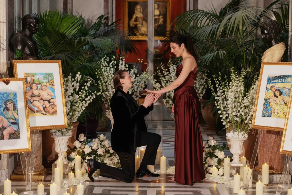 Man kneeling to propose with ring inside Musée Jacquemart-André's candlelit gallery, Paris