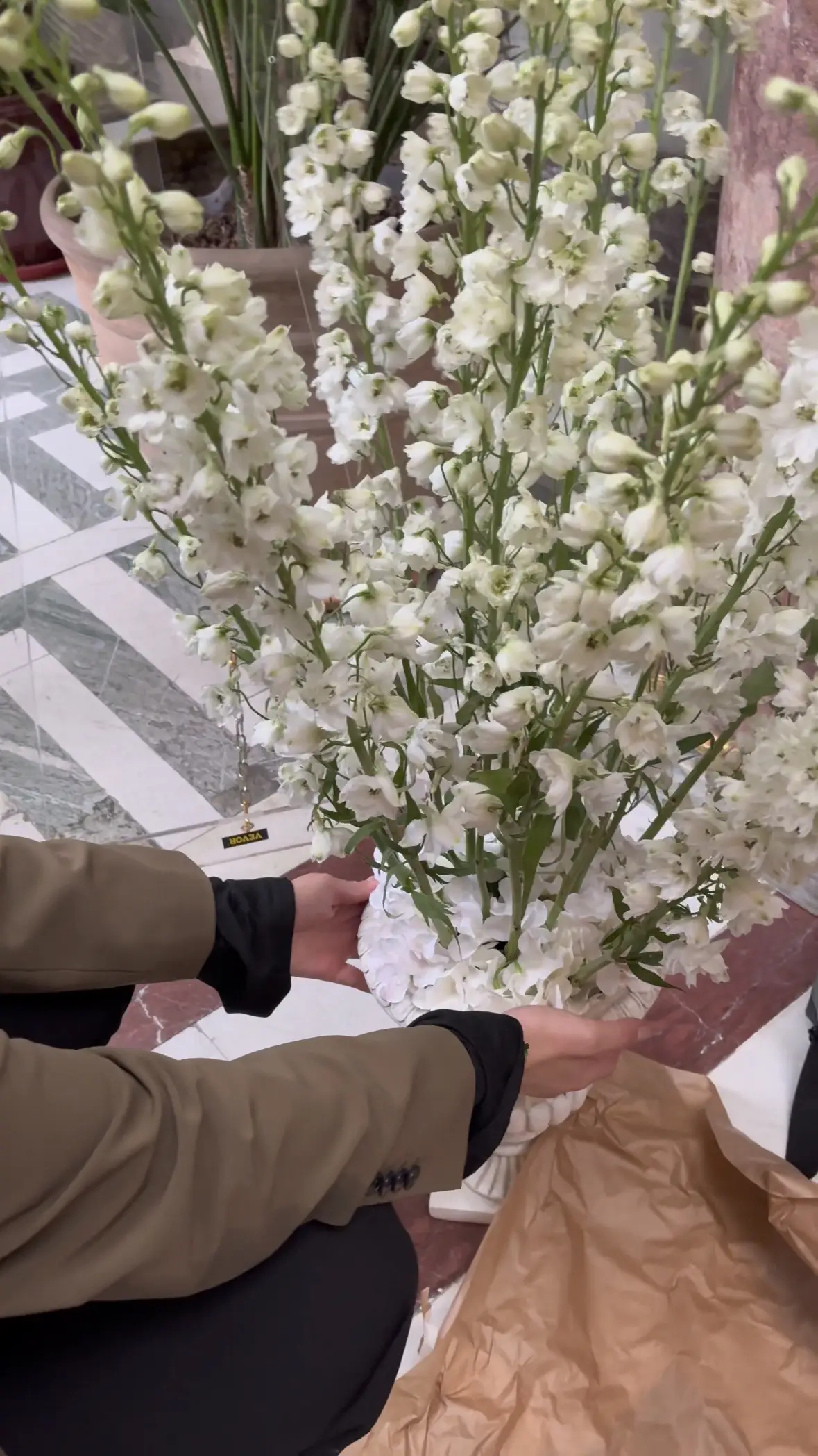 Florist arranging white delphinium in marble urn before a proposal setup at Musée Jacquemart-André