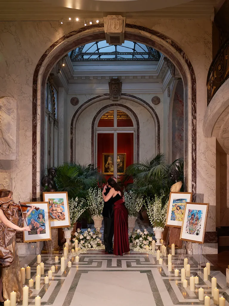 Wide view of candlelit aisle and live violinist with couple embracing at Musée Jacquemart-André, Paris