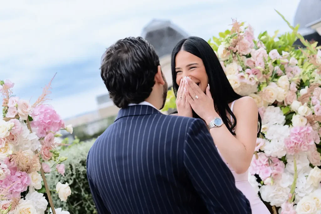 Woman covering her mouth in surprise with new engagement ring visible during Paris rooftop proposal