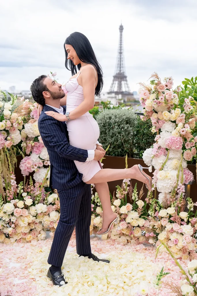 Man lifting his fiancée in celebration on The Peninsula Paris rooftop with Eiffel Tower in the background