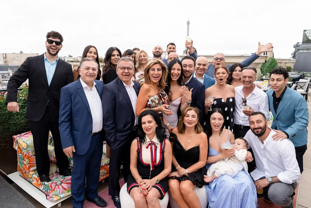Large family group celebrating an engagement on The Peninsula Paris rooftop with Eiffel Tower in the background