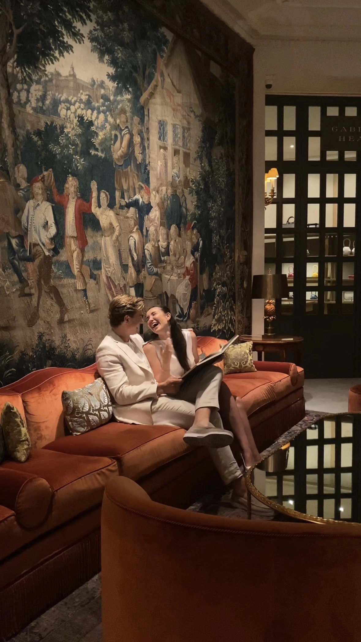 Newly engaged couple laughing together on velvet sofa in Le Bristol Paris lounge