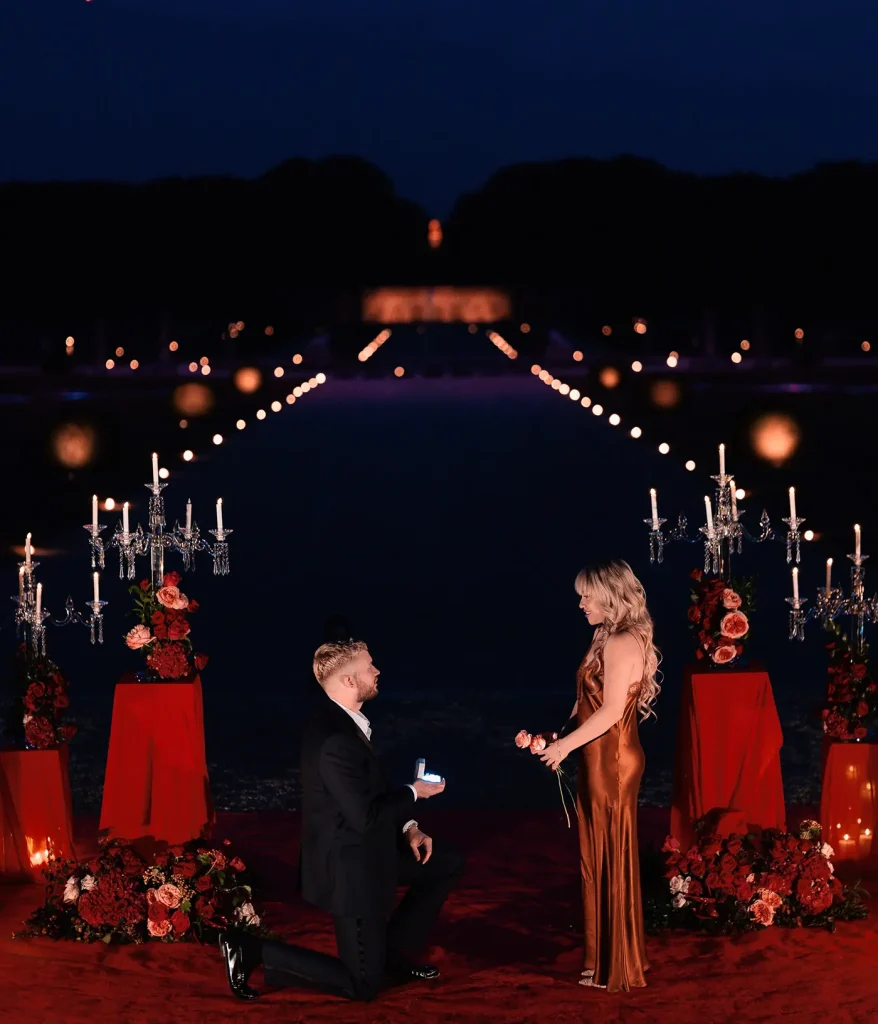 Man proposing on one knee in the candlelit gardens of Château de Vaux-le-Vicomte during a private proposal.