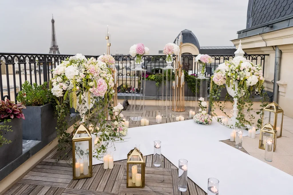 Rooftop proposal setup at The Peninsula Paris with pink and white floral arrangements, white aisle and Eiffel Tower view