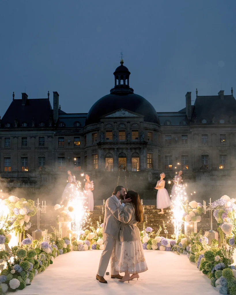 Couple kisses after proposal at Château de Vaux-le-Vicomte with ballerinas and firework fountains