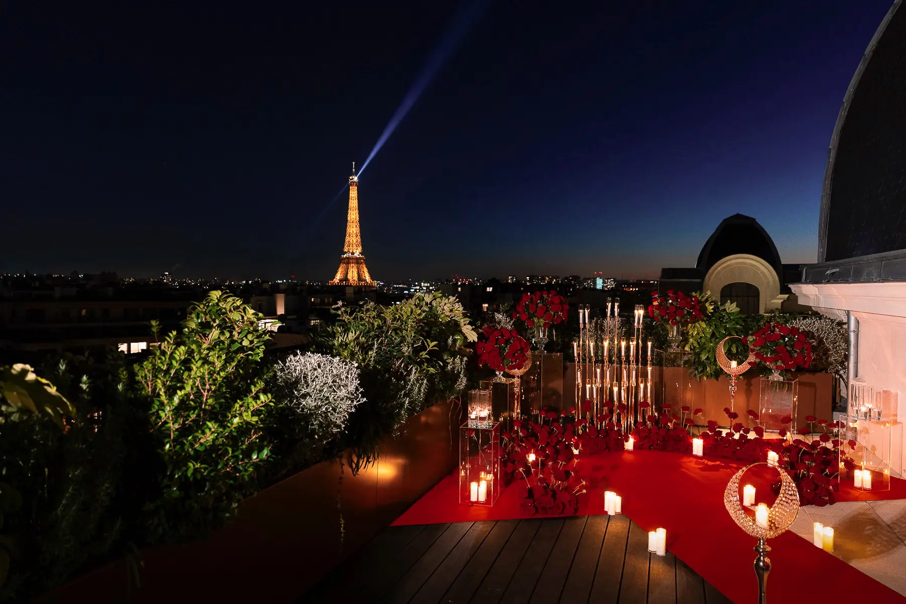 Private rooftop proposal setup at The Peninsula Paris Secret Table with red roses, candlelight, and the Eiffel Tower illuminated at dusk.
