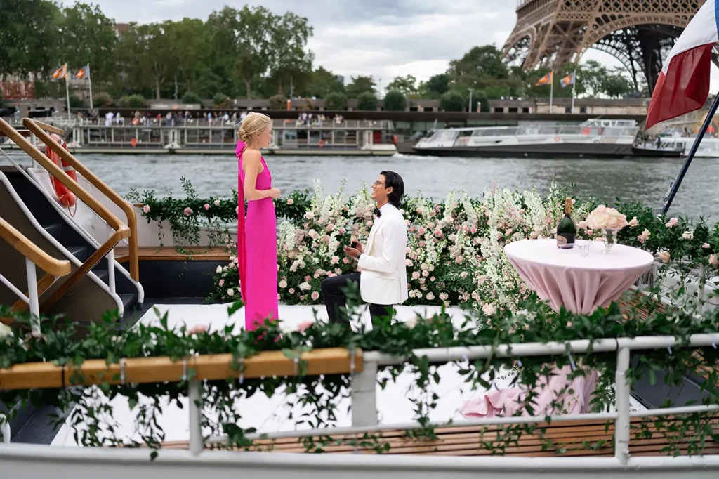 Man proposing on one knee on a private yacht on the Seine with the Eiffel Tower base visible behind them