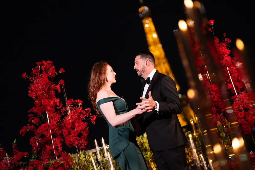 Couple holding hands and talking on The Shangri-La Paris terrace, framed by red roses and candlelight