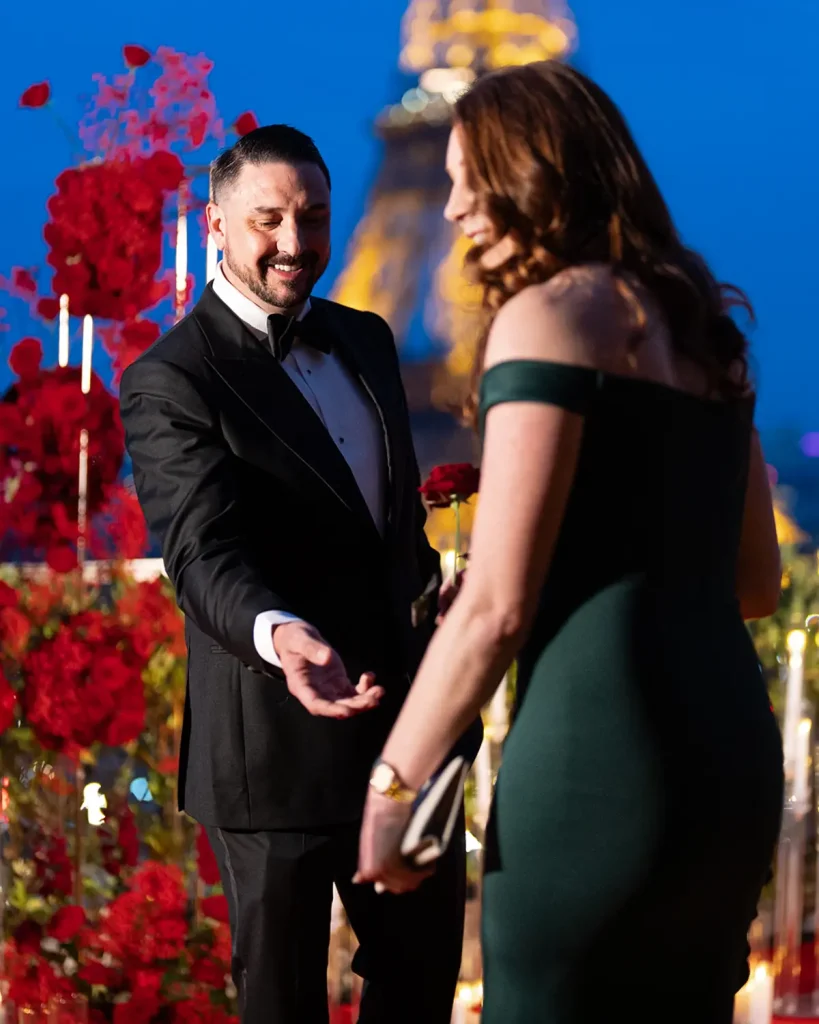 Man reaching for his partner's hand on The Shangri-La Paris terrace at blue hour, Eiffel Tower behind them