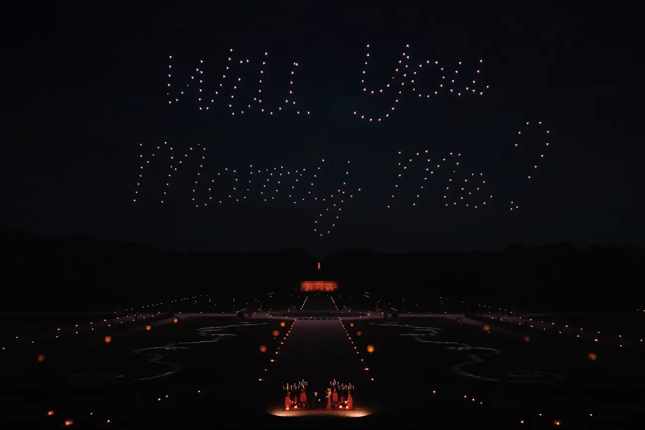 Drone light show spelling "Will You Marry Me" above the gardens of Château de Vaux-le-Vicomte at night