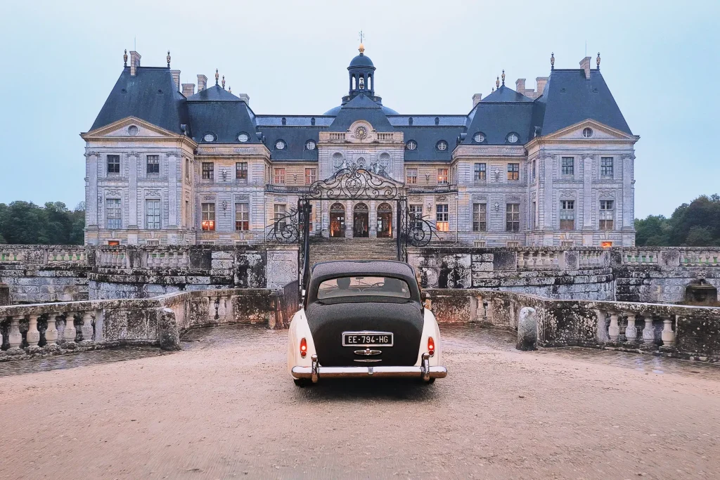 Vintage Rolls-Royce parked at the gates of Château de Vaux-le-Vicomte at dusk