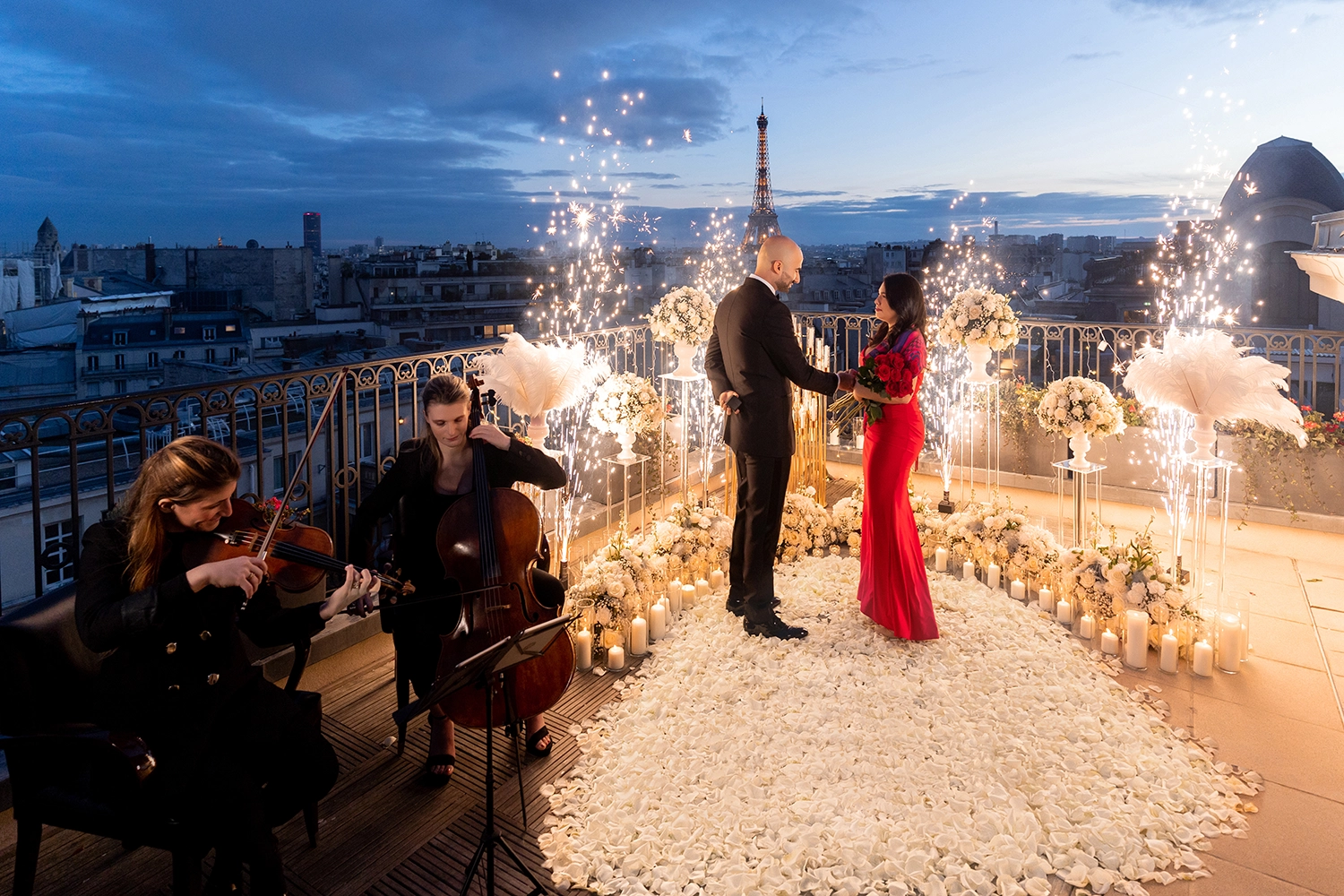 Couple celebrating a proposal at The Peninsula Paris as cold sparkler fountains light up around them at dusk