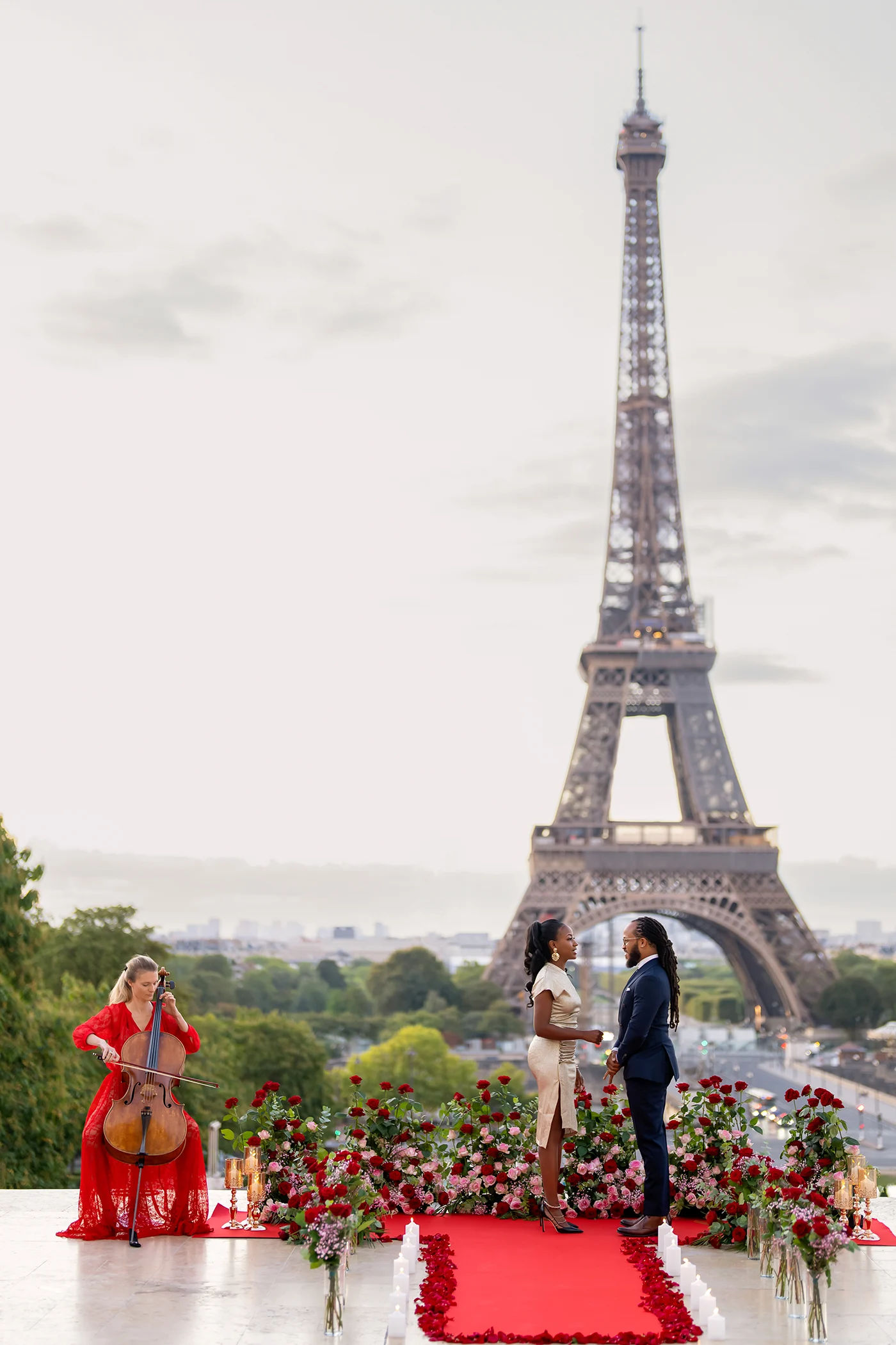 Couple facing each other during a Trocadéro proposal with a rose-lined aisle, cellist, and full Eiffel Tower behind them