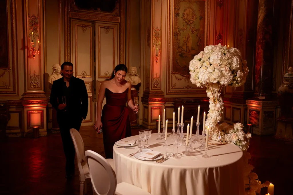 Couple arriving at private dinner table after proposal at Musée Jacquemart André Paris, tall floral centerpiece and taper candles