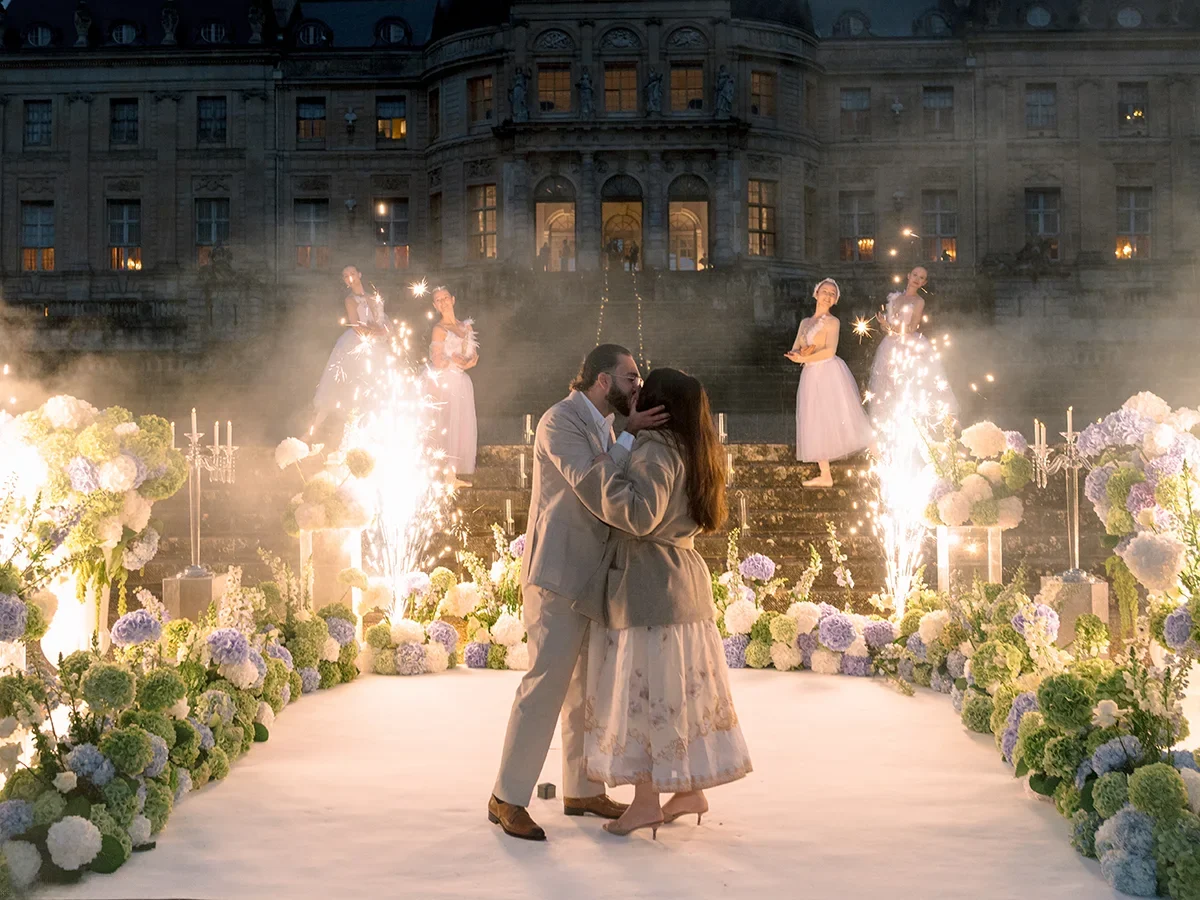 Couple kisses after proposal at Château de Vaux-le-Vicomte with ballerinas and firework fountains